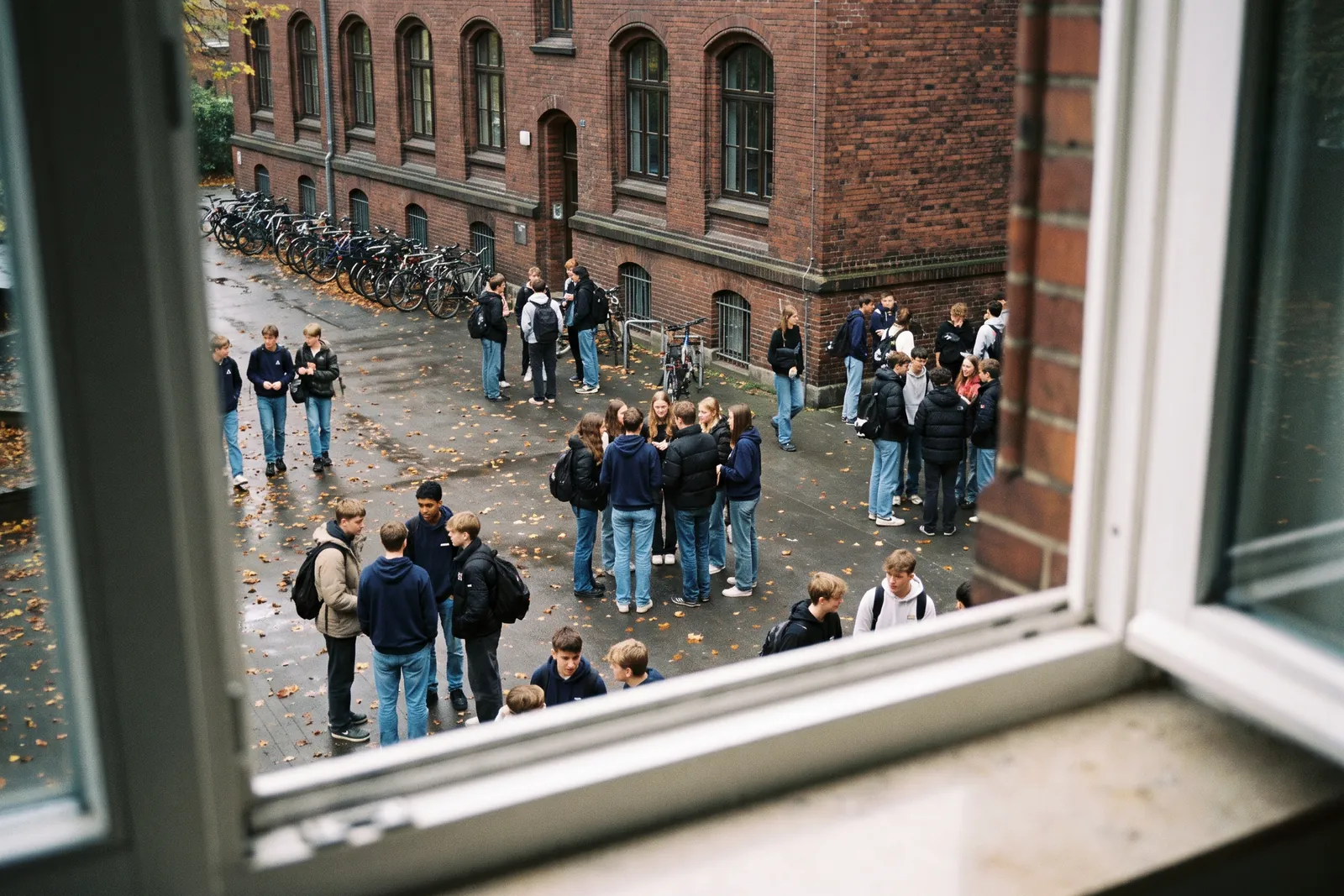 Blick von oben auf einen Schulhof in der Pause, einige Jugendliche tragen gleiche dunkelblaue Hoodies