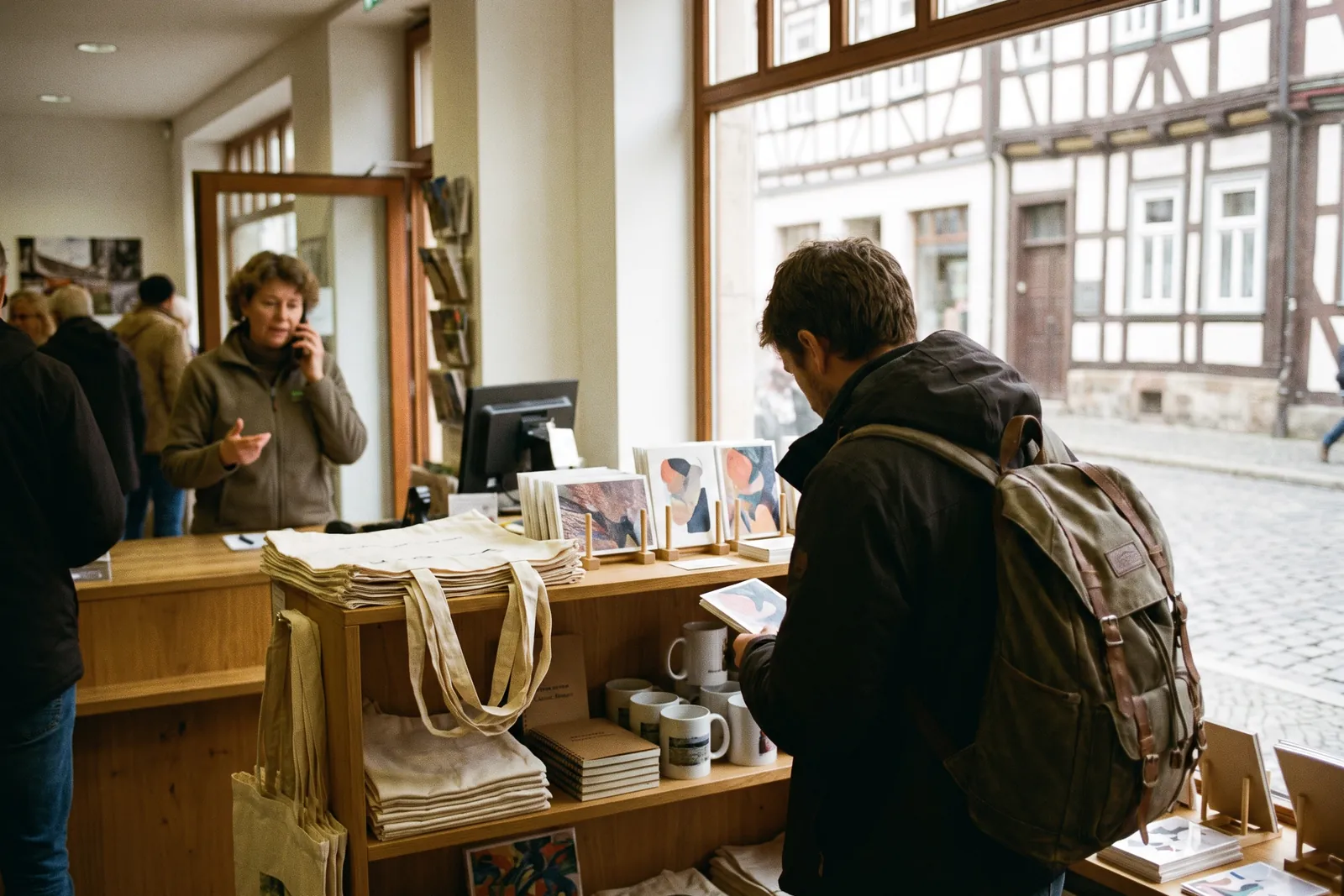 Visitor browsing the souvenir shelves of a tourist information office with bags, mugs and notebooks